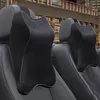 Zwei schwarze Auto-Nackenkissen mit Rautenmuster auf Autositzen, mit Stadtgebäude im Hintergrund Produktbild-Vorschau
