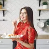 A woman in a red dress is eating sushi in a kitchen. Produktbild-Vorschau