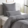A close-up view of a bed with gray pillows and bedding. Produktbild-Vorschau