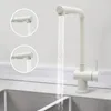 A white kitchen faucet with water flowing into a sink. Náhled obrázku produktu
