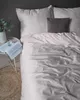 A neatly made bed with pink and white striped bedding, a dark gray accent pillow, a side table with a book and a plant. Anteprima dell’immagine prodotto
