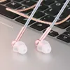Close-up of rose gold and white in-ear headphones resting on a laptop keyboard. Produktbild-Vorschau