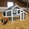 A chicken coop is set up on a bed of straw inside a barn, with a rooster standing in front of it. Produktbild-Vorschau