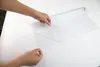 Hands are peeling a protective film off a translucent sheet on a white surface. Voir les images du produit