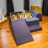 A young child is playing in a ball pit with colorful balls, surrounded by soft play equipment. Produktbild-Vorschau