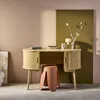 A wooden desk with a stool in front of it, set against a pink and olive green wall. Produktbild-Vorschau