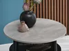 A round coffee table with decorative items on top, set against a blue wall and wooden slats. Produktbild-Vorschau