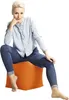 A woman is sitting on an orange cube ottoman. Náhled obrázku produktu