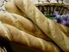 Several baguettes are arranged in a basket, with some chives and purple flowers in the background. Náhled obrázku produktu