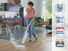 A woman is using a steam cleaner in a modern kitchen and living room area. There are promotional overlays on the right side of the image. Náhled obrázku produktu