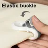 A hand is shown using an elastic buckle to secure a piece of fabric, likely a duvet cover. Produktbild-Vorschau
