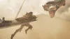 A warrior in armor is running with a large sword, facing a dragon's head in a dusty, atmospheric environment. Produktbild-Vorschau