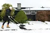 A person is shoveling snow in front of a house. Produktbild-Vorschau