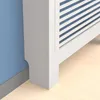 A close-up view of the bottom corner of a white radiator cover with blue slats, placed next to a blue wall and on a light wood floor. Anteprima dell’immagine prodotto
