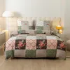 A neatly made bed with a patchwork-style duvet cover and pillows. Náhled obrázku produktu