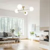 A modern living room with a large window overlooking a forest, featuring a sofa, coffee tables, and a fireplace. Produktbild-Vorschau