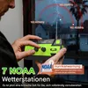 A person is holding a green and black emergency radio in front of a window during a storm. Produktbild-Vorschau