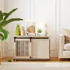 A dog crate is placed in a living room setting next to a sofa, with decorative items on top. Náhled obrázku produktu