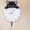 A black and white cat-shaped wall clock with a fish-shaped pendulum. Produktbild-Vorschau