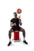 A man is sitting on a red stool and juggling a basketball. Produktbild-Vorschau