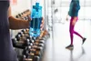 A person holds a blue Nalgene water bottle in a gym setting, with dumbbells in the background and another person walking in the distance. Produktbild-Vorschau