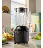 A black Philips blender sits on a kitchen counter, with fruits like bananas and apples in the background. Náhľad obrázku produktu