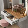 A vanity table with drawers open, displaying makeup and decorative items, next to a pink stool. Voir les images du produit