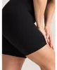 Schwarze nahtlose High-Waist-Shorts, von einer Person getragen, von der Seite gezeigt, mit Händen auf dem Oberschenkel Náhled obrázku produktu