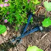 Two black landscape staples are placed on the ground near green plants and purple flowers. Náhľad obrázku produktu