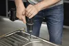 A person is using a drill to make a hole in a stainless steel sink. Produktbild-Vorschau