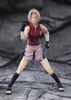 A full-body shot of an action figure of Sakura Haruno from Naruto Shippuden, posed in a fighting stance against a rocky, gray background. Náhled obrázku produktu