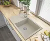 A modern kitchen sink area with a granite sink, faucet, and countertop, with plants and window blinds in the background. Podgląd zdjęcia produktu