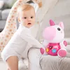 A baby is playing with a plush unicorn toy next to a large giraffe stuffed animal. Anteprima dell’immagine prodotto