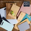 A collection of various cutting boards of different colors and materials, arranged on a wooden surface. Two lime halves are placed on one of the wooden cutting boards. Anteprima dell’immagine prodotto