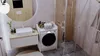 A modern bathroom with a washing machine, sink, and shower. Produktbild-Vorschau