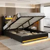 A modern bedroom with a black upholstered bed frame open to reveal storage space underneath. The bed has an LED-lit headboard. Náhľad obrázku produktu
