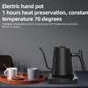 A black electric gooseneck kettle is displayed on its charging base, next to two mugs and a glass on a wooden tray. Náhled obrázku produktu