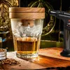 A whiskey glass with smoke and a smoking gun on a wooden table. Voir les images du produit