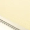 A close-up, angled view of a cream-colored pleated blind with thin white horizontal lines, set against a white background with a metallic track at the bottom. Produktbild-Vorschau