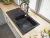 A modern kitchen sink with a black granite basin and a chrome faucet, set on a light wood countertop. Podgląd zdjęcia produktu