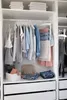 A well-organized closet with clothes neatly hung and folded, and storage baskets on shelves. Anteprima dell’immagine prodotto
