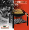 A couple is shown in the background, while a fire pit with a mesh cover and a wooden poker is in the foreground. The image is split between a black and white section and a red section. Produktbild-Vorschau