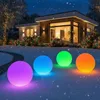 Four illuminated spheres in various colors are placed on the snow in front of a modern house decorated with Christmas lights. Anteprima dell’immagine prodotto