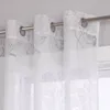 Close-up view of white sheer curtains with a floral pattern hanging on a curtain rod. Produktbild-Vorschau