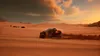 A buggy racing through sand dunes at sunset. Produktbild-Vorschau