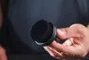 A hand holds a black applicator brush with a black handle and a black brush head. Anteprima dell’immagine prodotto