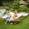 A couple relaxing in a hammock in a garden setting with a pool and lush greenery. Náhled obrázku produktu