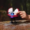 A child's hand is interacting with a small, red and white robot toy on a rocky, outdoor surface with a blurred forest background. Anteprima dell’immagine prodotto
