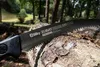 A close-up of a Silky Zübat saw resting on a log in a forest setting. Produktbild-Vorschau