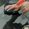 A person is cleaning a shiny black surface with a cloth and spray bottle. Anteprima dell’immagine prodotto